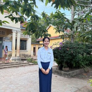 TDSO Teacher development and support organisation outdoor scene with a smiling woman in formal attire.