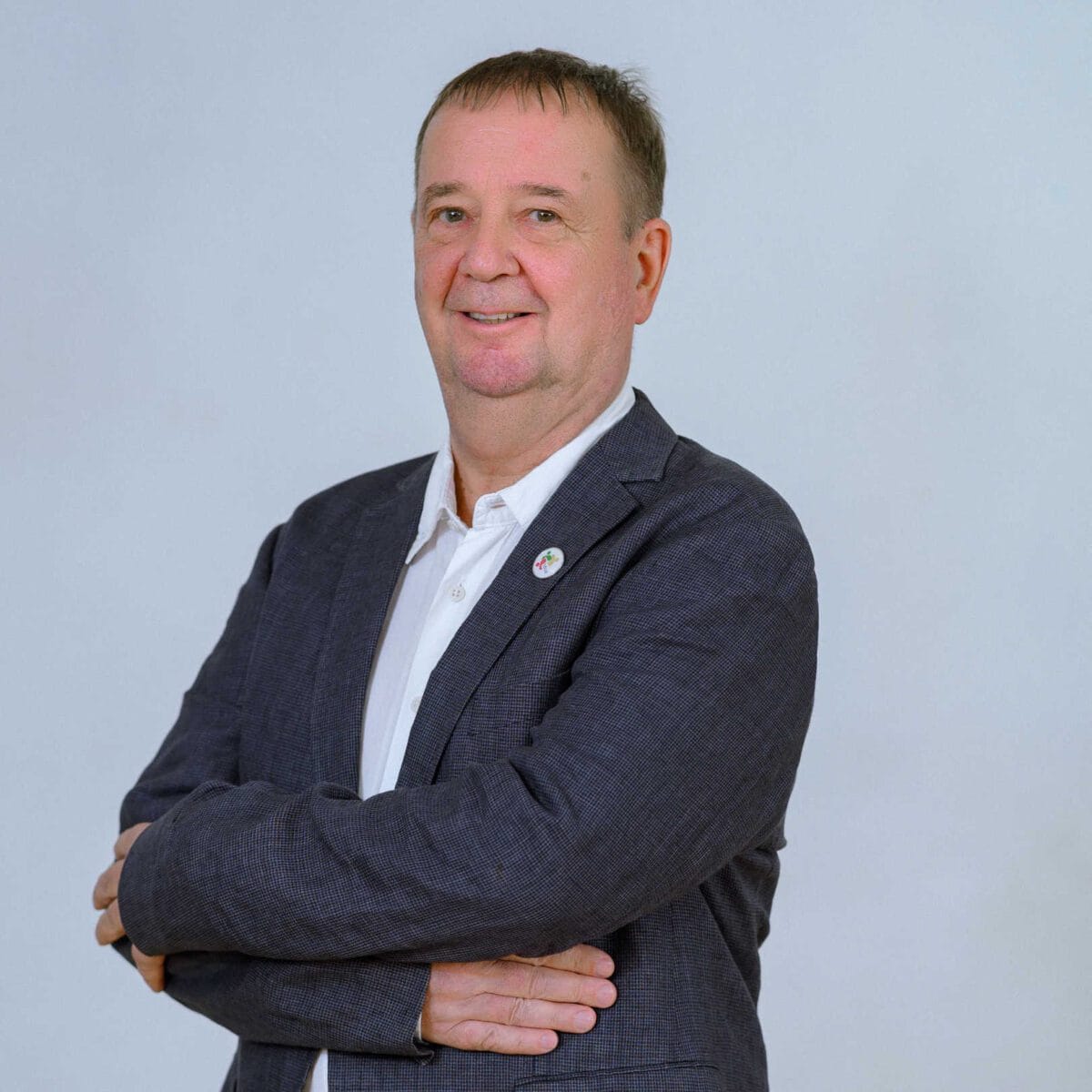 TDSO Professional male educator in a suit with arms crossed, smiling confidently.