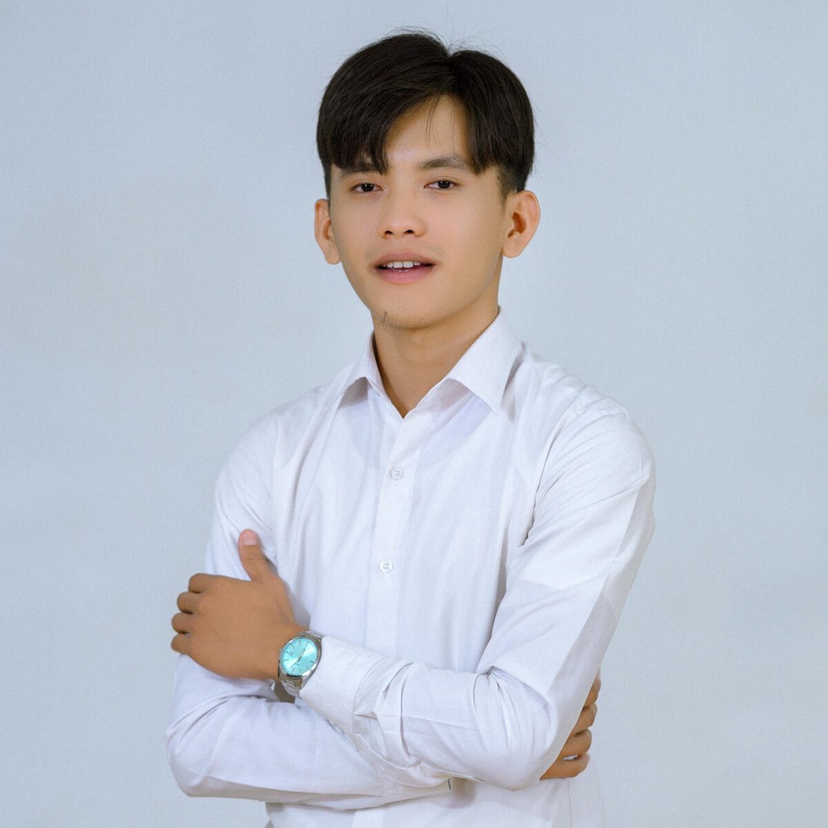 TDSO Young teacher in white shirt with crossed arms, smiling confidently.