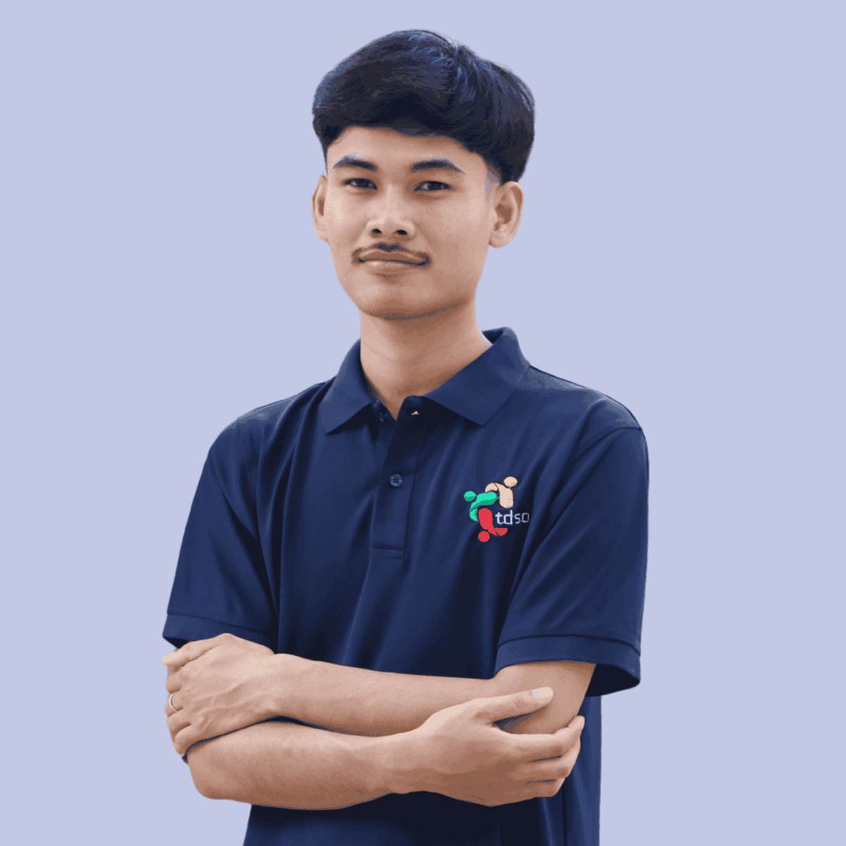 TDSO Young teacher wearing TDSO organisation polo shirt, standing confidently with arms crossed.